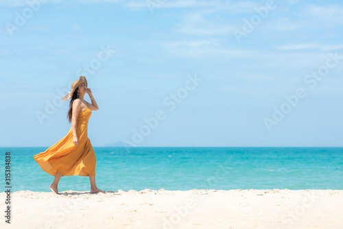 Summer Holiday. Lifestyle woman chill with wearing yellow dress fashion summer trips walking chill on the sandy ocean beach. Happy people enjoy and relax vacation. Lifestyle and Travel Concept.