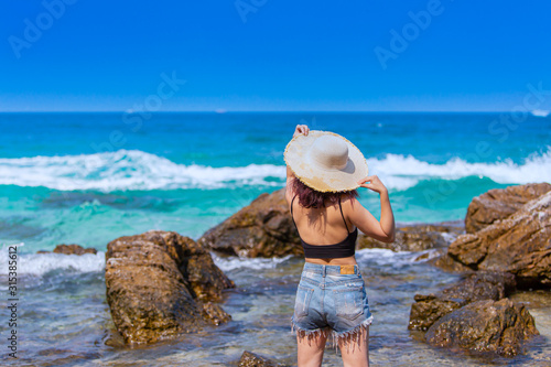 Summer beach traveller woman in casual wear with hat enjoys her tropical beach vacation