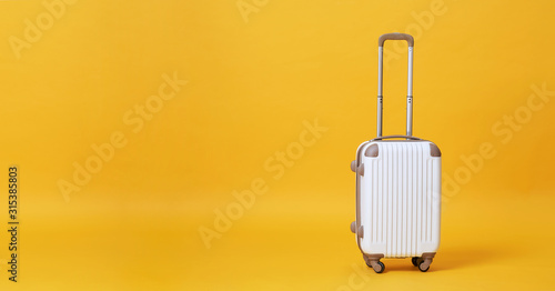 White luggage bag isolated on yellow banner background with copy space for advertisement.. photo