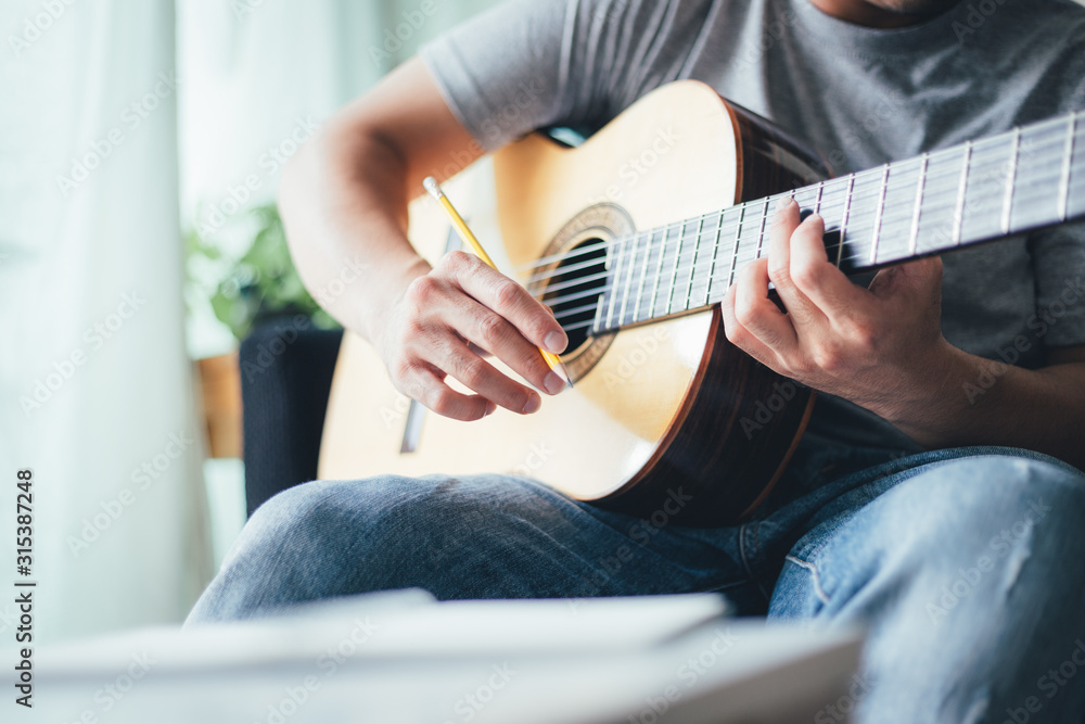 Fototapeta premium artist songwriter thinking writing notes,lyrics in book at studio.man playing live acoustic guitar relax chill.concept for musician creative.composer work process.people relaxing time with instrument