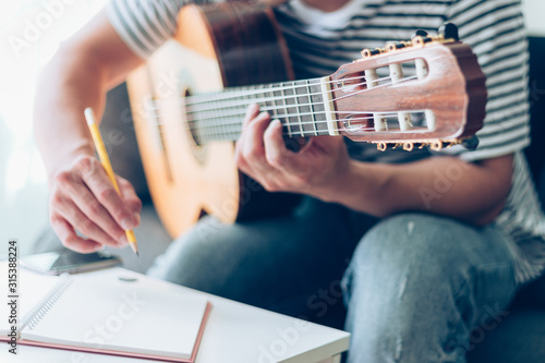 artist songwriter thinking writing notes,lyrics in book at studio.man playing live acoustic guitar relax chill.concept for musician creative.composer work process.people relaxing time with instrument