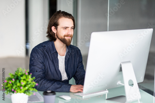 Young bearded man working at xomputer in modern office