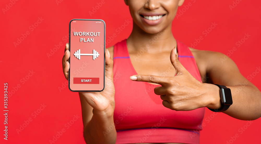 Fitness lady pointing at workout application on phone screen - obrazy, fototapety, plakaty 