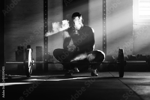 Bodybuilder preparing his hands with powder for weightlifting in a gym.