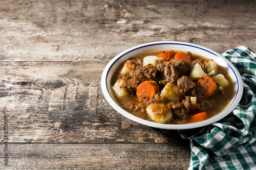 Irish beef stew with carrots and potatoes on wooden table. Copy space