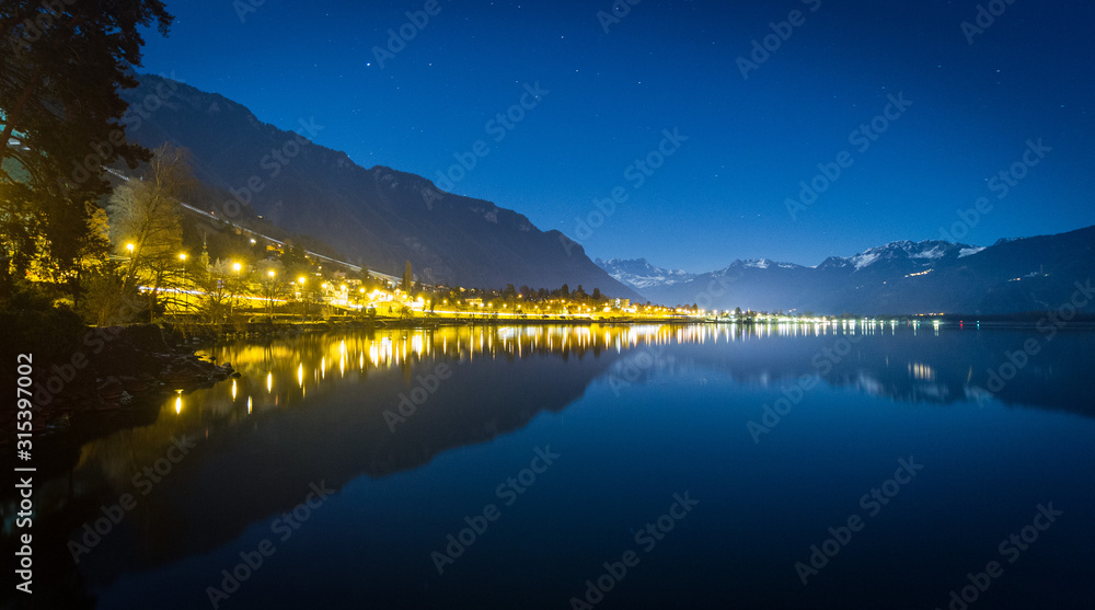 Lake shore lit up at night, reflection, blue night