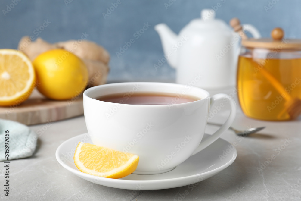 Fresh tea with honey and lemon on light grey marble table, closeup