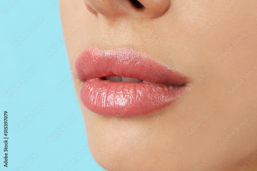 Woman with beautiful full lips on light blue background, closeup Woman with beautiful full lips on light blue background, closeup