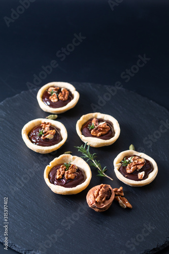 Food concept Homemade rustic organic mini chocolate and walnuts tarts on black slate stone plate with copy space