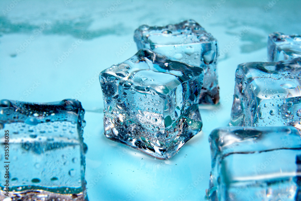 Ice cubes / Wet ice cubes on blue glossy background / Close up / Copy space for text Ice cubes / Wet ice cubes on blue glossy background / Close up / Copy space for text