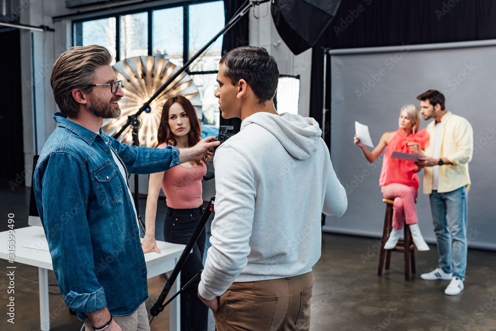happy art director looking at handsome assistant in photo studio happy art director looking at handsome assistant in photo studio
