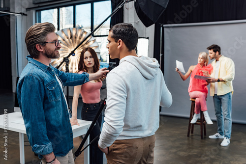 happy art director looking at handsome assistant in photo studio © LIGHTFIELD STUDIOS