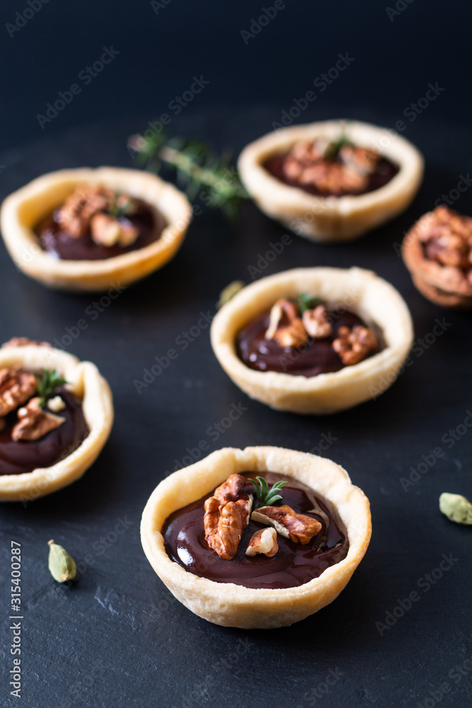 Food concept Homemade rustic organic mini chocolate and walnuts tarts on black slate stone plate with copy space
