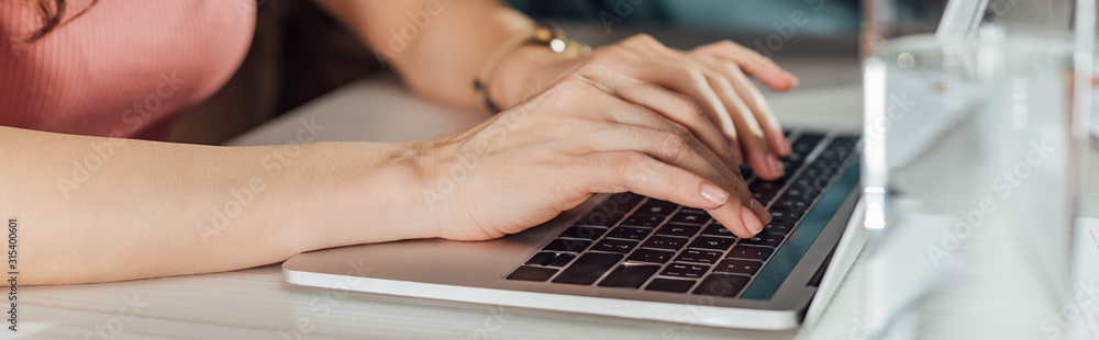 panoramic shot of art director typing on laptop keyboard panoramic shot of art director typing on laptop keyboard