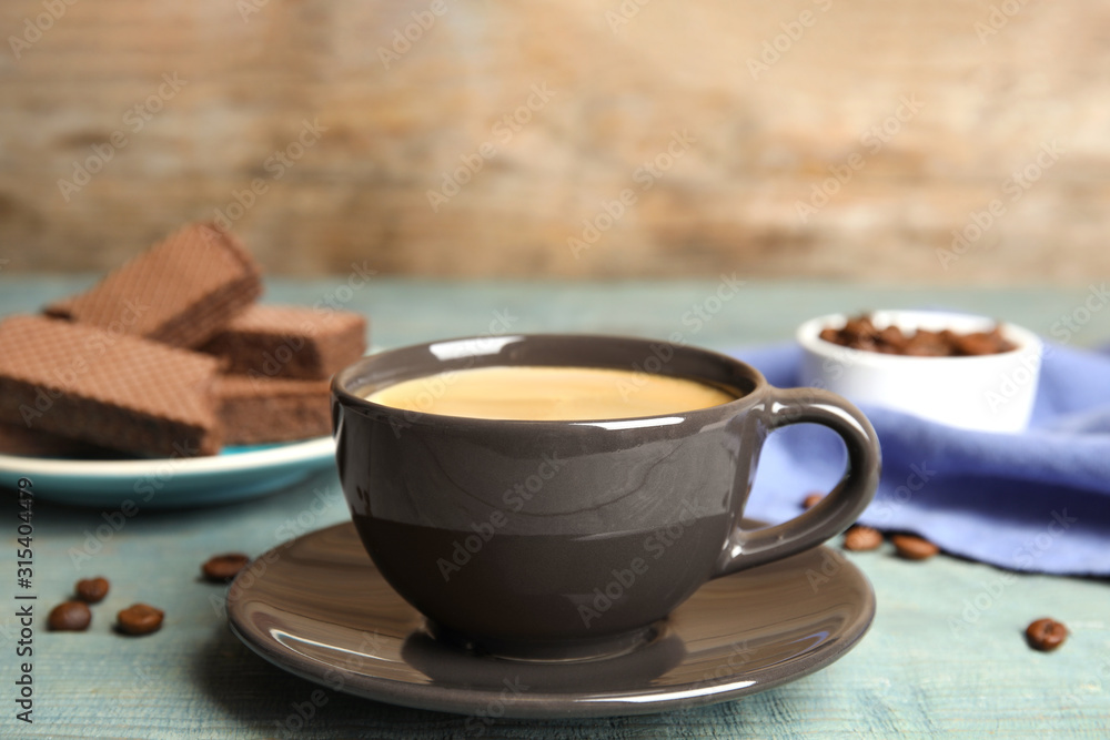 Fototapeta Delicious coffee and wafers for breakfast on light blue wooden table