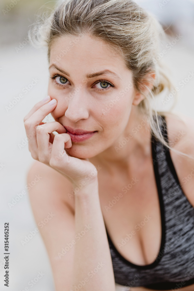 Content young female athlete in stylish sports outfit leaning hands on knees while training looking at camera Content young female athlete in stylish sports outfit leaning hands on knees while training looking at camera