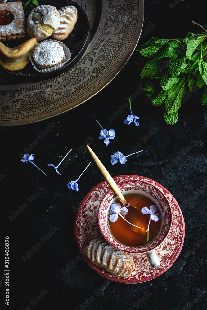 Traditional tea with mint and assorted homedade Arab sweets on dark ...