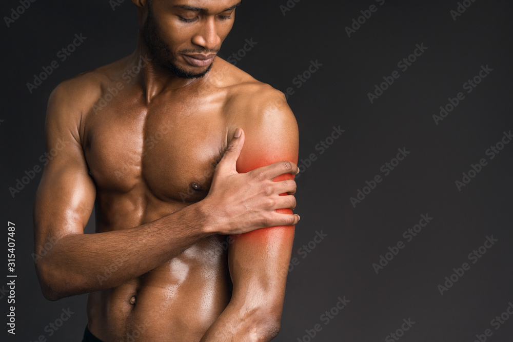Handsome shirtless afro man suffering from pain in arm
