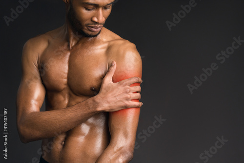 Handsome shirtless afro man suffering from pain in arm