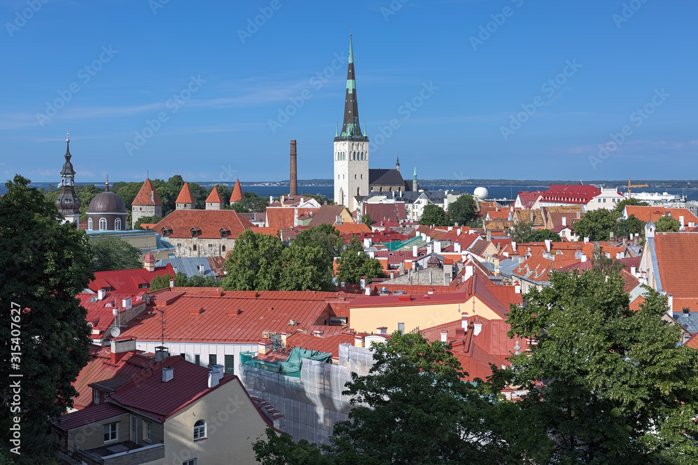 Tallinn, Estonia. Lower Town with St. Olaf's Church, Transfiguration Cathedral, towers of Tallinn City Wall, and Tallinn Bay of Baltic Sea in the background. View from the Kohtuosa viewing platform.