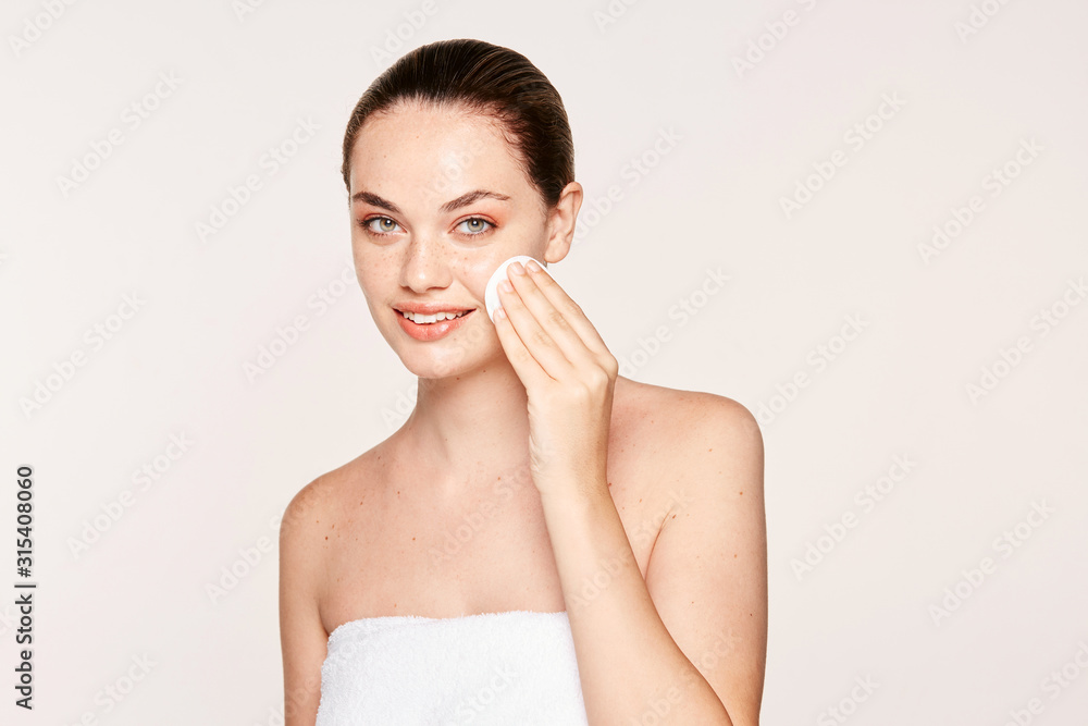 Peaceful female applying toner on radiant face with sponge Peaceful female applying toner on radiant face with sponge