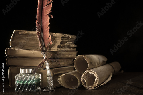 Quill pen and rolled up papyrus sheets  with old books, vintage effect