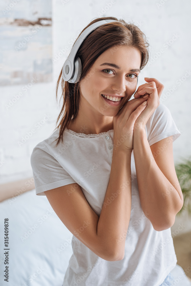 Fototapeta premium smiling woman looking at camera while listening music at home