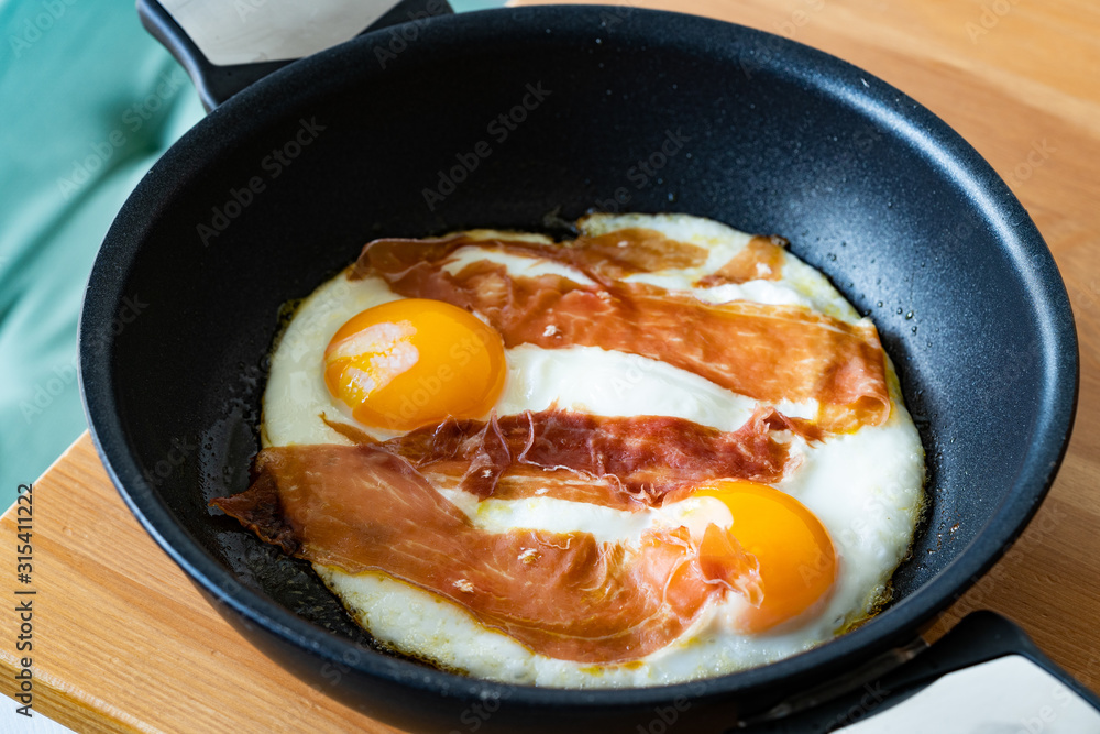 Fried Eggs with Prosciutto in Pan for Breakfast. Ready to Eat. Fried Eggs with Prosciutto in Pan for Breakfast. Ready to Eat.