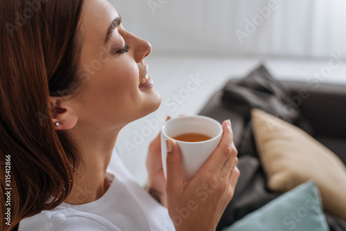side view of attractive woman holding cup with tea