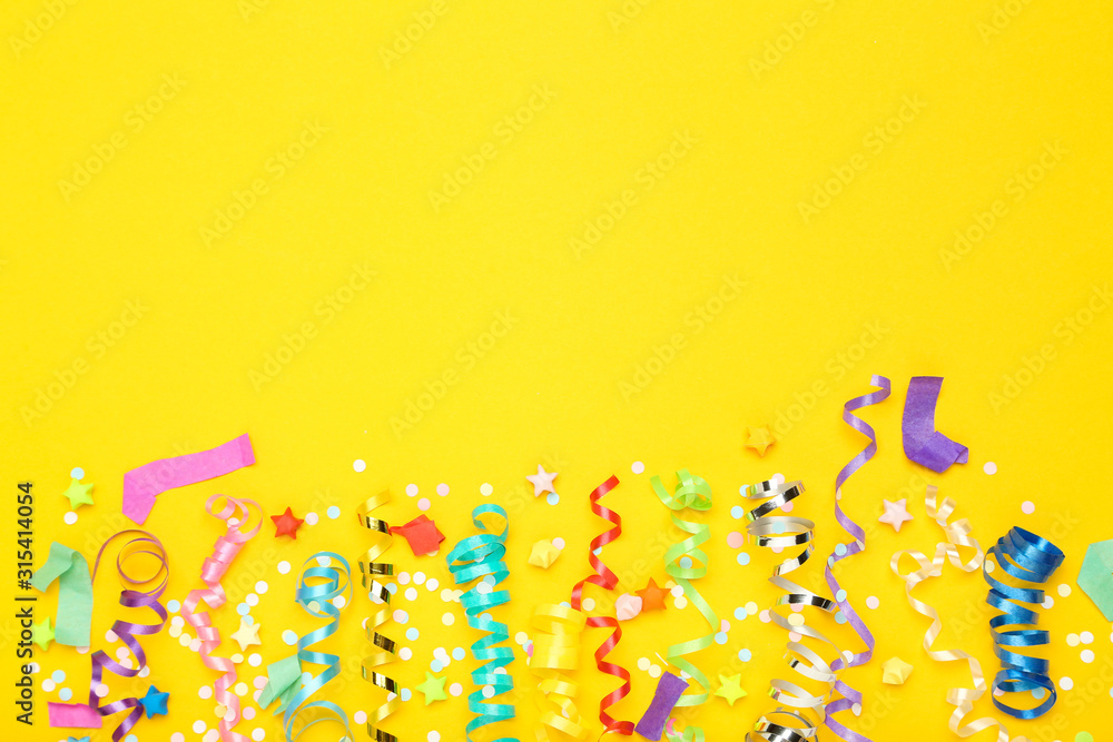 Colorful ribbons with paper stars and confetti on yellow background - obrazy, fototapety, plakaty 