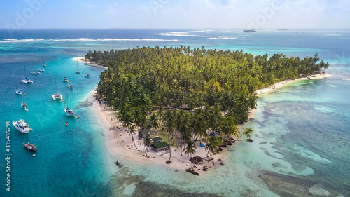 Aerial View of the San Blas Islands in Panama. Sailing Yachts & Sailboats anchoring next to Tropical Island with green Palm Trees and white sand Beaches surrounded by Coral Reefs in the Caribbean Sea. photo