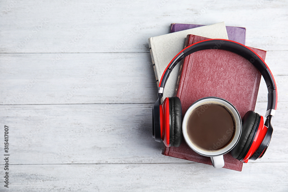 Books, coffee and headphones on white wooden table, top view. Space for text