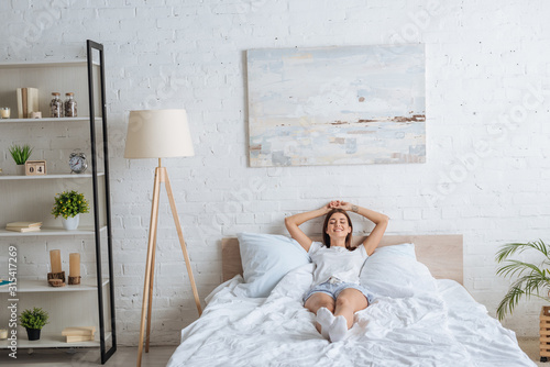 happy woman with tattoo lying while resting in bedroom