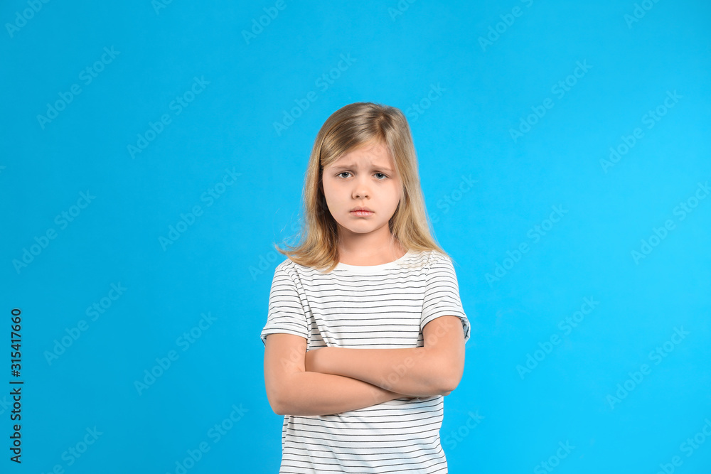 Upset little girl on light blue background Upset little girl on light blue background