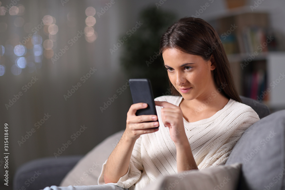 Girl checking mobile phone content sitting in the night at home Girl checking mobile phone content sitting in the night at home