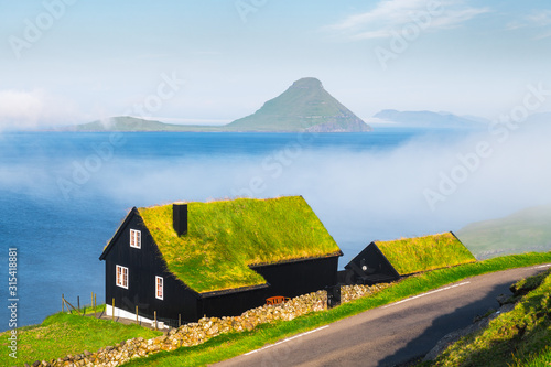 Foggy morning view of a house with typical turf-top grass roof in the Velbastadur village on Streymoy island, Faroe islands, Denmark. Landscape photography photo