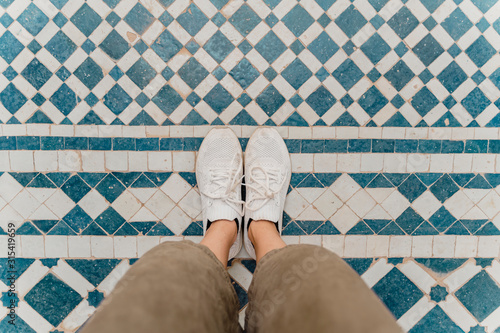 Woman's feet standing on traditionally tiled floor, Fez, Morocco