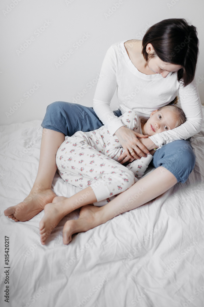 Mother hugging her daughter on bed Mother hugging her daughter on bed