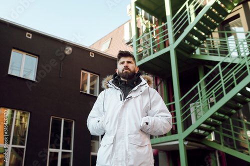 Young beard man in white parka on the street photo