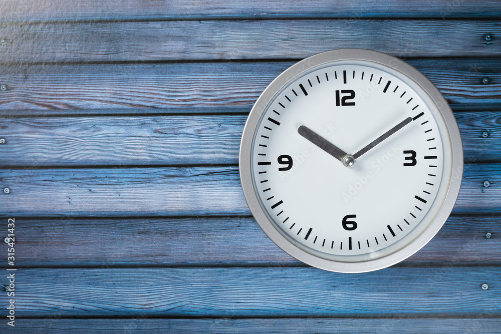 White wall clock with a yellow used hanging on the wall. Minimalist image of a wall clock on a wooden background with copy space White wall clock with a yellow used hanging on the wall. Minimalist image of a wall clock on a wooden background with copy space