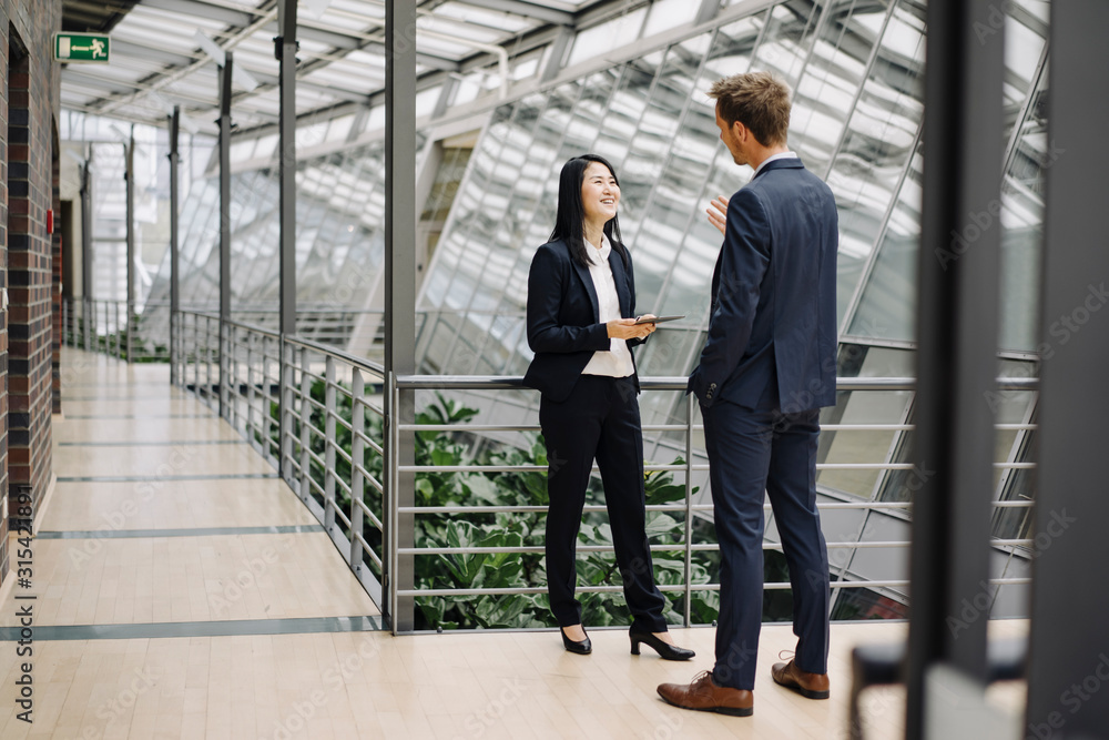 Businessman and businesswoman with tablet talking in modern office building Businessman and businesswoman with tablet talking in modern office building