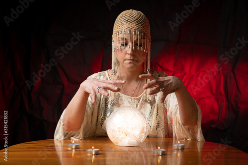 Wall Mural Fortune Teller with Crystal Ball on table with candles and black and red mottled