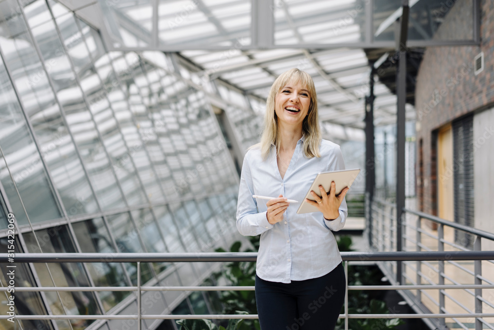 Laughing young businesswoman in a modern office building using tablet Laughing young businesswoman in a modern office building using tablet