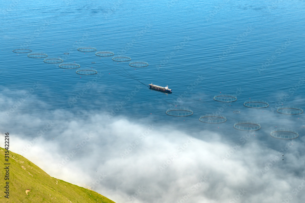 Fototapeta premium Fish farm with ship on foggy fjords of Funningur, Eysturoy island, Faroe Islands. Landscape photography