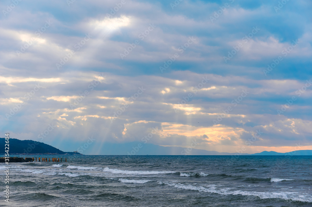 Sunlight beams through the clouds on the beach in a winter day