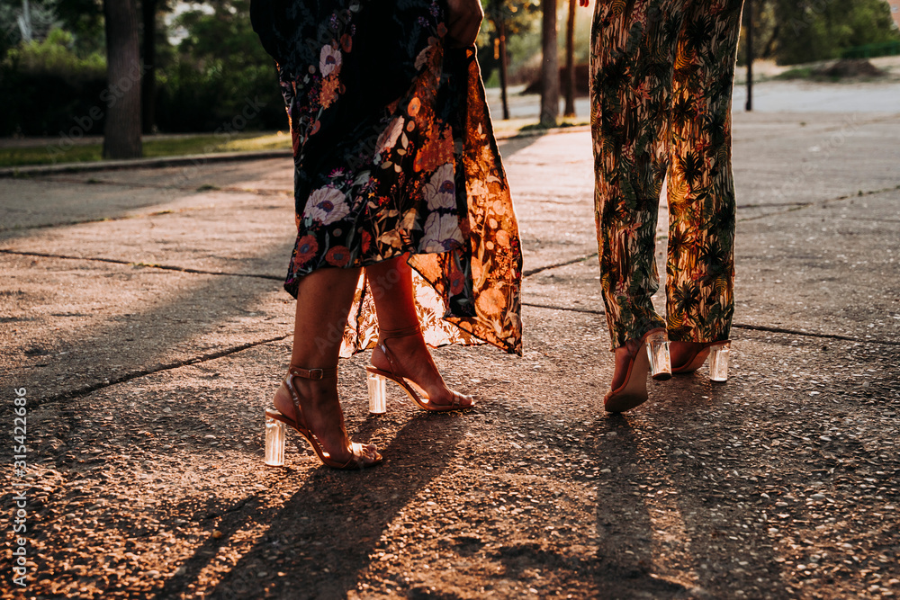 Feet of two elegant women walking outdoors at sunset Feet of two elegant women walking outdoors at sunset