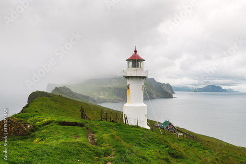 Foggy view of old lighthouse on the Mykines island, Faroe islands, Denmark. Landscape photography