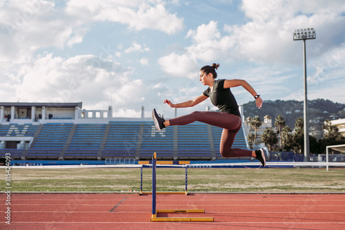 Female hurdler during training on tartan track photo