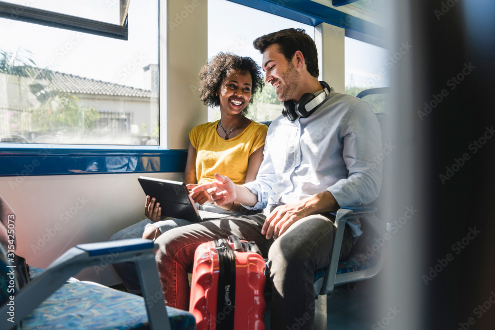 Happy young couple using tablet in a train Happy young couple using tablet in a train