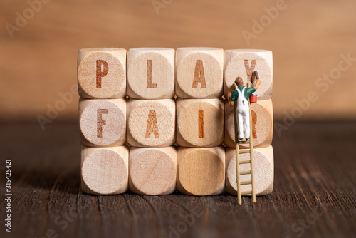 cubes with the message "play fair" on wooden background